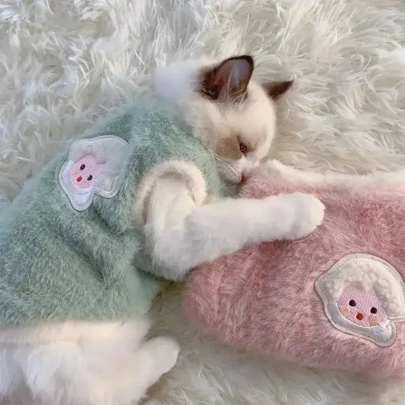 Chaton dormant avec un animal en peluche portant un vêtement en fausse fourrure